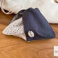 Détail du denim bleu foncé avec broderie en dentelle blanche et logo de marque JUEDE - Pince à cheveux nœud en dentelle patchwork gris et blanc