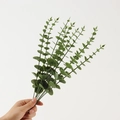 Single green artificial eucalyptus leaf branch held by hand for home wedding decor - Light Green