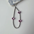 Dettaglio di perline a cuore rosa e sfere metalliche argentate su un laccetto da borsa - Tre Cuori Rosso Rosa