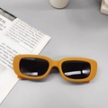 Detail of trendy rectangle sunglasses with bold orange frames and dark lenses - Yellow