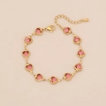 Detail van roze hartvormige edelstenen op een gouden stalen ketting met karabijnsluiting - Waterrood