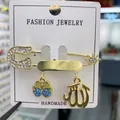 Goldene Hamsa-Hand-Brosche mit blauem Kristall und arabischer Kalligrafie-Anhänger - Hellblau Buchstabe