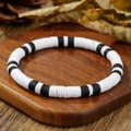 Bohemian style black and white clay bead bracelet on a natural wood and leaf background - ZJ15041-Black and White Flat Round Clay Bracelet