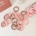 Primer plano de gomas de pelo de colores con un tarro de almacenamiento transparente - Serie Rosa