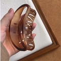 Matte bernsteinfarbene Haarklammer aus Harz in Schildpatt-Optik in der Hand gehalten - B-Hohler Bogen (Bernsteinbraun Matt)