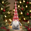 Détail d'un gnome de Noël avec bonnet rouge à flocons et corps rayé gris sur fond festif - Poupée Gnome au Chapeau Rouge