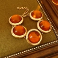 Macro shot of gold bracelet with five amber resin stones on green textured fabric backdrop - Gold & Coffee Bracelet