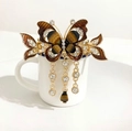 Detailed view of a brown and gold butterfly hair claw clip with sparkling rhinestone tassels - Brown