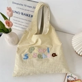 Détail d'un sac cabas à carreaux jaunes avec broderie colorée dans un cadre cosy - Jaune