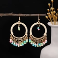 Detailed shot of bohemian round earrings with pastel seed bead tassels on a branch - Colorful