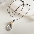 Detail van zilveren onregelmatige metalen hanger en beige keramische kraal op zwart koord - Zilver