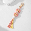 Macro detail of handmade knit daisy keychain with pink yellow and white cotton petals - Orange Yellow Flower