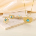 Dettaglio di parure dorata a ventaglio con pietra turchese su sfondo di tessuto beige - Stile Trama Semicircolare con Pietra Preziosa Blu (KS220677-LX)