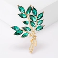 Macro-opname van gouden tarwebroche met groene kristallen op witte display - Groen