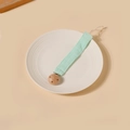 Détail d'une attache-tétine en coton vert menthe avec pince en hêtre sur une assiette - Style Vert Menthe (13)