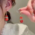 Detailed view of red enamel Christmas earrings with diamond accents on a model - Red Snowman