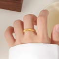Detailed view of a gold titanium ring with fine ripple texture worn on a finger - US 5 / Gold