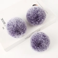Three purple faux rabbit fur pom poms on a white book for handbag keychain DIY - Purple Frost / Light Gold 4-Link Lobster Clasp