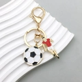 Gouden sleutelhanger met zwart-witte voetbal en een rood-wit sportshirt hangertje - Voetbalspeler Hanger (ER769)