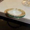 Detailansicht eines gold Armbands mit smaragdgrünen und weißen Zirkonia-Steinen - Grüner runder Zirkonia-Stil