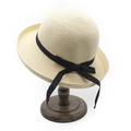 Detail van beige geweven strohoed met zwarte strik op een donkerhouten hoedenstandaard - M(56-58cm) / Beige