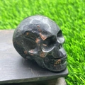 Polished 5cm Bloodstone crystal skull carving with reddish-brown spots on dark stone - Plum Blossom Jade