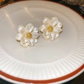 Detalle macro de pendientes de camelia con pétalos perlados y centro dorado - Pendientes de botón de flor con aguja de plata / Blanco
