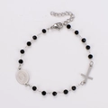 Detalle de pulsera de rosario con cuentas negras facetadas, cruz de plata y medalla central - Color Acero