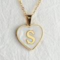 Macro view of a gold heart pendant with shell inlay and the letter S - Letter S / Gold