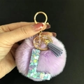 Gros plan d'un porte-clés pompon violet avec pendentif lettre L en résine et métal doré - Lettre L