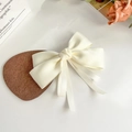 Detailopname van een crèmekleurige satijnen strik met lange linten en haarclip - Beige