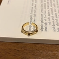 Detail macro-opname van een 18k vergulde tijgeroog ring op een open geslagen boek - Pave Zirconia Stijl / Goud