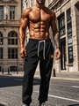 Men's relaxed black joggers with white drawstring and gold tips in urban street setting - Black