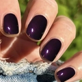 Dettaglio ravvicinato di unghie finte viola scuro lucido su sfondo di tessuto denim - Viola Profondo Specchio Lucido (CW269)