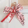 Detail of red polka dot silk bow keychain with a golden spring ring clasp and woven cord - No.6 (Red and White Polka Dot)