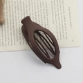 Matte dark brown oval hair claw clip displayed on a book page with natural props - Matte Dark Coffee