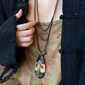 Close-up of bohemian ethnic water-drop necklace with button and tassel detail on model - Bohemian Teardrop Bow Style / Brown and Green
