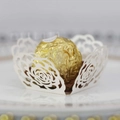 Vue macro d'un support à chocolat en papier blanc découpé au laser avec motif rose ajouré - Ivoire