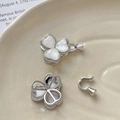 Macro shot of silver clover-shaped pearl connectors with white inlay on ceramic dish - White Gold