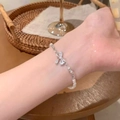 Macro detail of silver bow pearl bracelet with zircon stone on a female wrist - S649 Silver