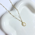 Detail macro van de gouden kralenketting met een ovale edelsteen hanger op een blad - Witte Schelp