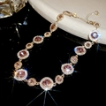 Detailansicht der luxuriösen Goldhalskette mit funkelnden rosa Kristallen und Diamant-Halo - Halskette - Gold - Violett