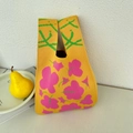 Detail of yellow knit handbag featuring pink flower patterns with a fresh pear on the side - Small Yellow Flowers