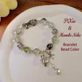 Ethnic beaded bracelet with green natural stones and silver lucky charms on white plate - Green Ghost: Pixiu Fortune Cat Bracelet