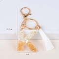 Detail of letter K keychain featuring white resin stones, gold foil, and long silk tassel - Letter K