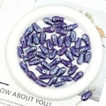 Detailed view of purple ceramic fish beads with evil eye design for DIY jewelry making - Violet