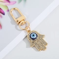 Detail of gold Hamsa hand keychain featuring sparkling rhinestones and a blue evil eye bead - Medium Gold Hamsa Hand 9