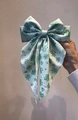 Elegant mint green clover print satin bow hair clip held against a neutral wall - Mint Green With Green Shamrock (3)