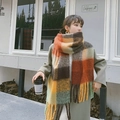Plaid tassel scarf in orange and brown tones worn by model in a cafe setting - Orange Brown Green Beige Check