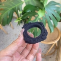 Close-up of black ruffled fabric scrunchie with elastic texture in a natural setting - Black